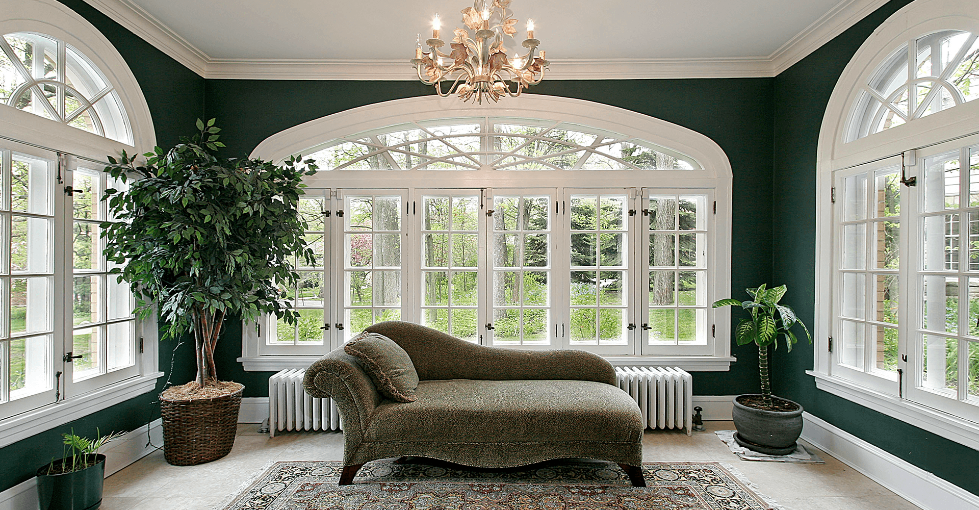 Hinged windows in a dark green sun room with white trim.